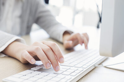Ein Mensch schreibt mit den Händen auf einer Computer Tastatur.